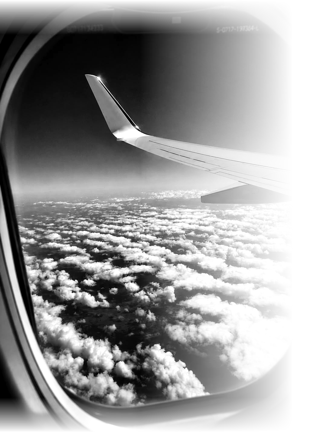 View from an airplane window over clouds, black and white